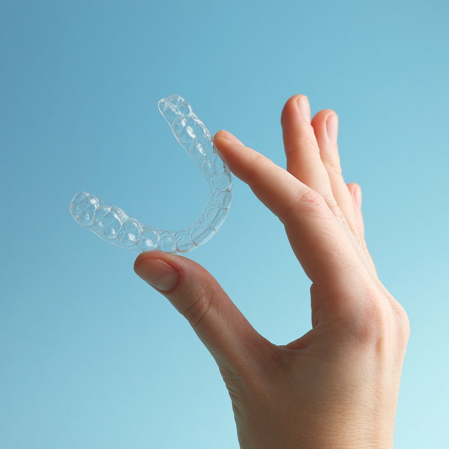 A hand model displays an Upper Teeth Custom Clear Retainer, its clear and durable design - Clear retainer after braces care - Snap Custom Nightguards